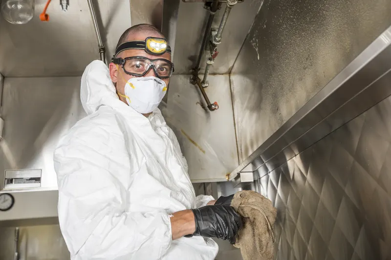 Close view of the filter channel along the lower edge of a stainless steel exhaust hood after degreasing